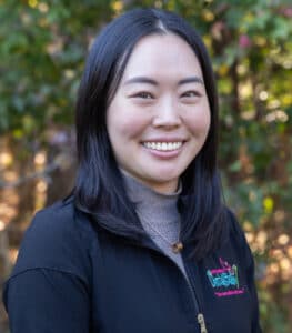 Portrait of Dr. Sophie Jo, DDS, smiling outdoors while wearing a black dental practice jacket.