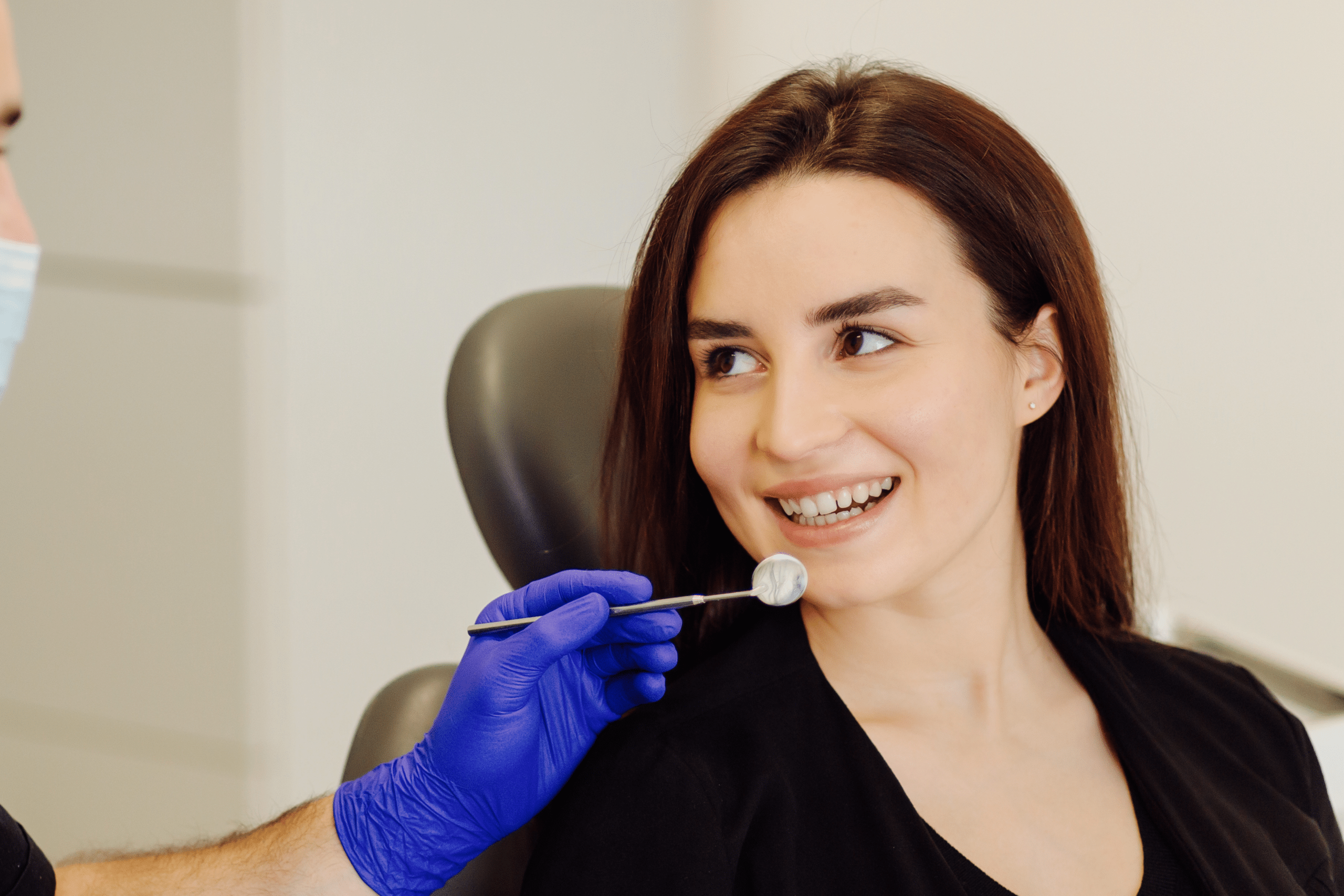 Smiling patient during a cosmetic dentistry consultation with a dentist examining teeth