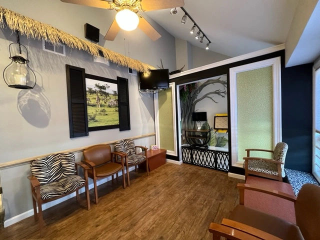 Safari themed waiting room at Adult & Pediatric Dental Studio featuring zebra-print chairs, nature murals, and jungle-inspired décor