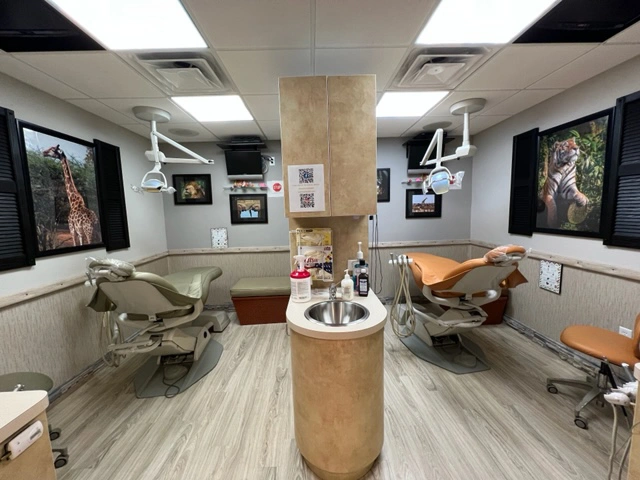 Pediatric dental treatment room with TVs and animal-themed decorations