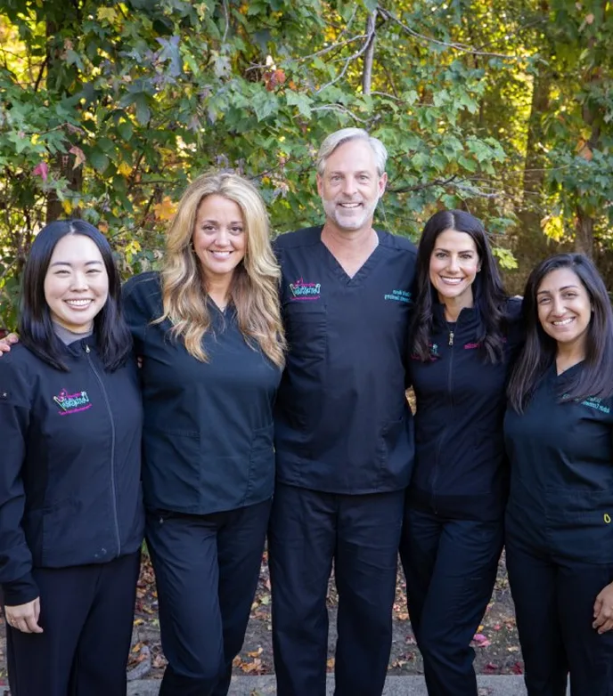 The dental team at Adult & Pediatric Dental Studio smiling together outdoors in matching black scrubs