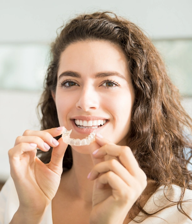 Woman holding clear aligner trays for orthodontic treatment at Adult & Pediatric Dental Studio