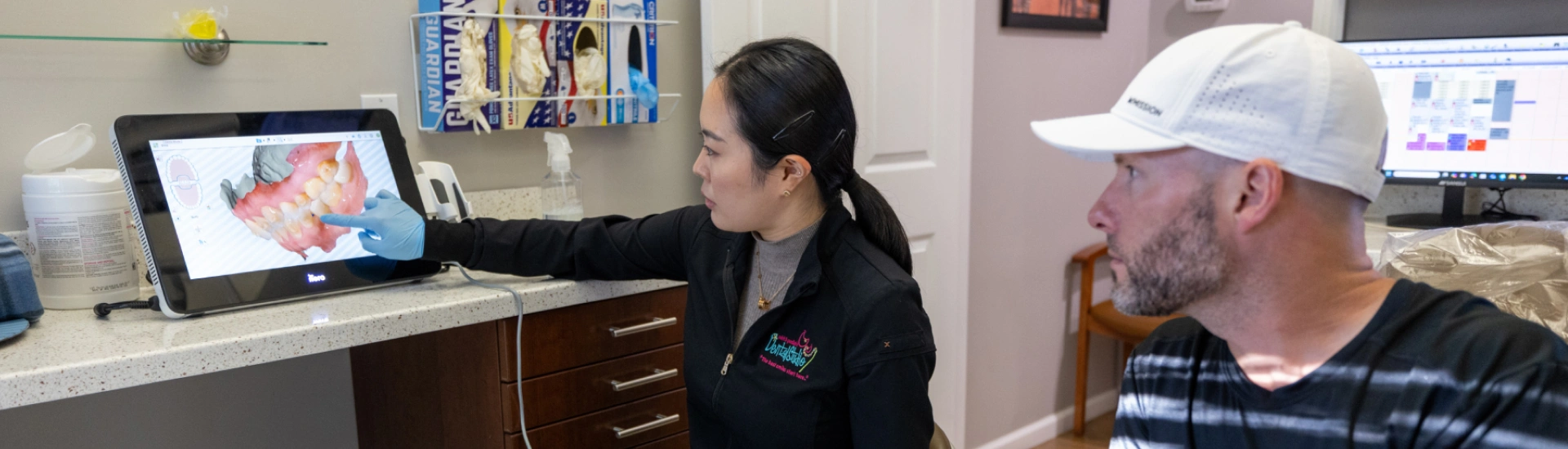 A clinical professional explaining a digital 3D model of an orthodontic treatment plan to an adult patient