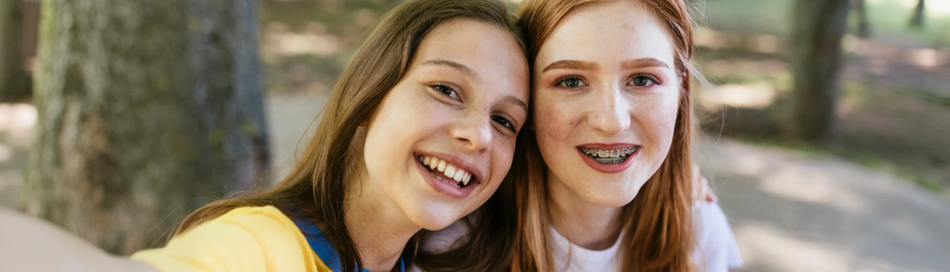 Two happy adolescent friends posing for a close-up photo outside
