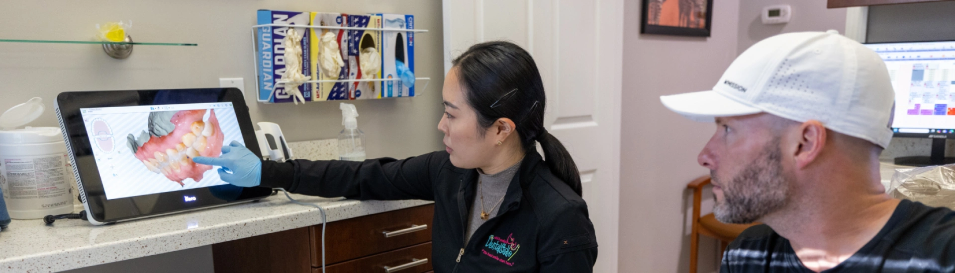 A dentist demonstrating advanced intraoral scanning technology to a patient in a treatment room