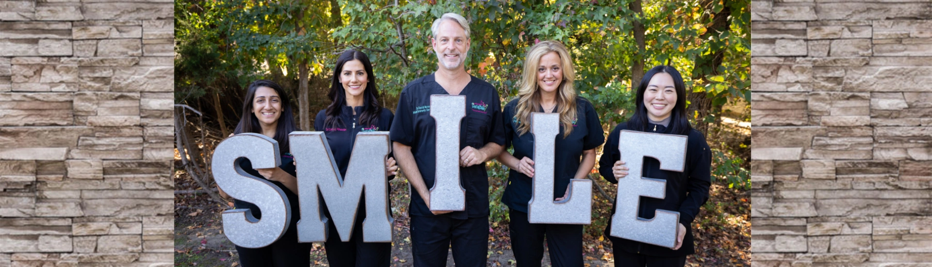 Dental team banner photo with staff members holding "SMILE" letters
