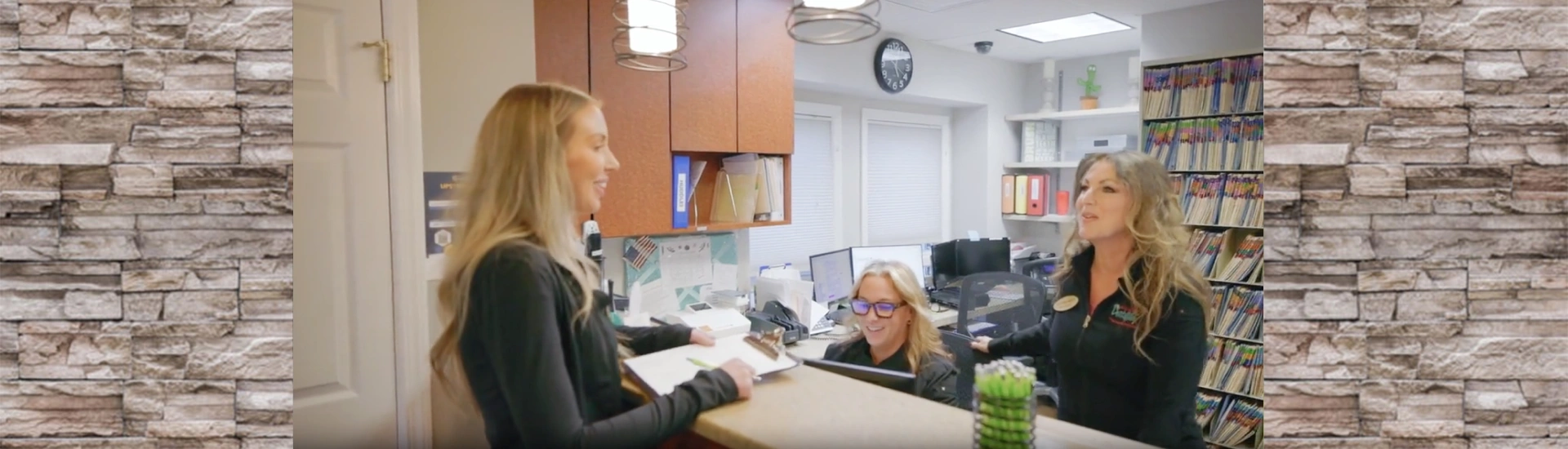 A friendly interaction between a patient and the office staff at a dental reception counter