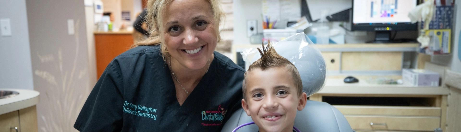 Dr. Kerry Gallagher smiling alongside a happy young patient at Adult & Pediatric Dental Studio